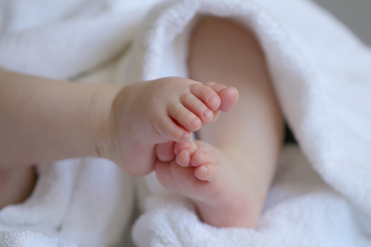 Close-up of a baby's feet nestled in a white blanket.